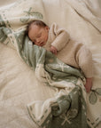 Newborn baby wrapped in a green and white tennis blanket