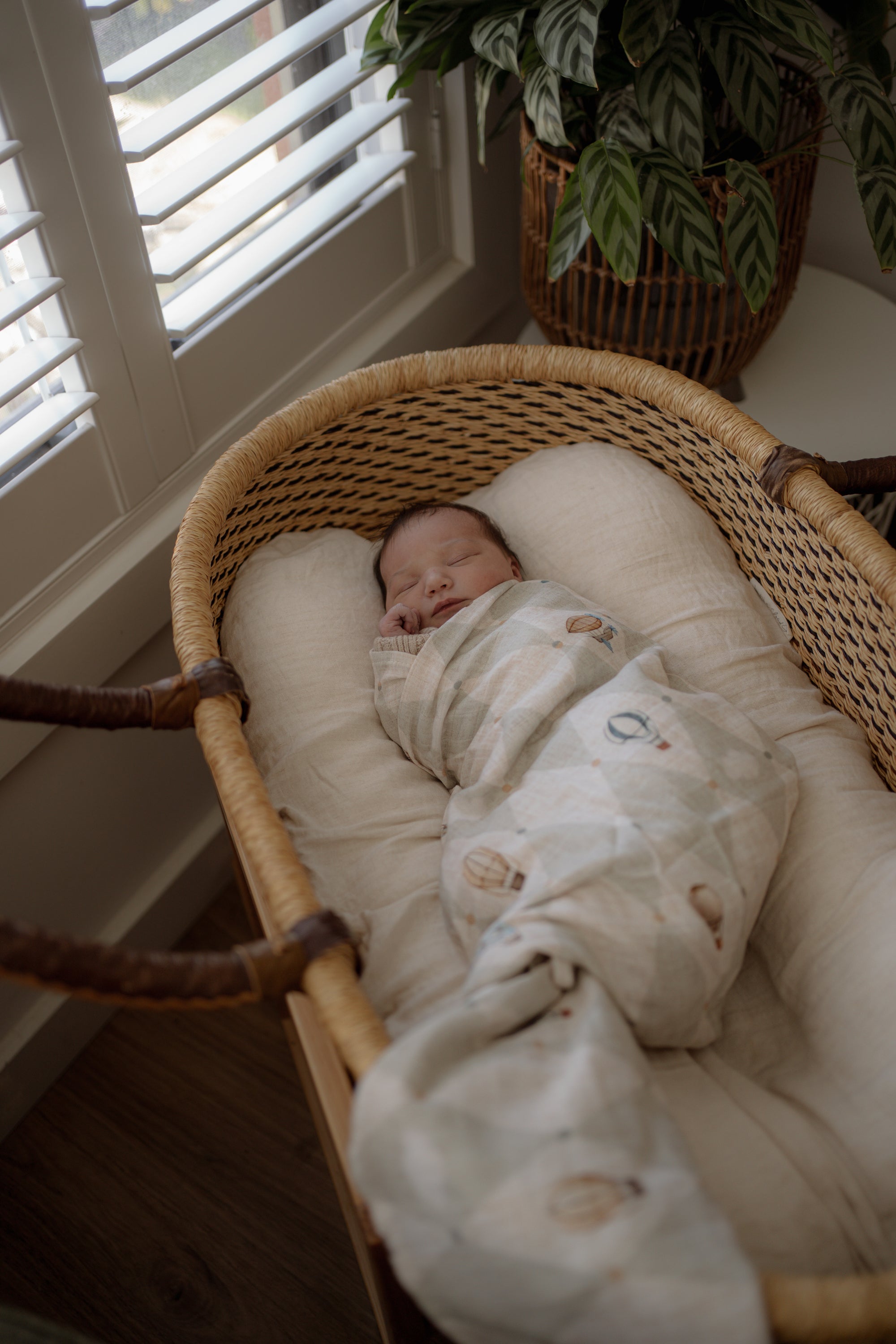 Newborn baby photography, sleeping in a wicker bassinet with pop yat tot swaddle