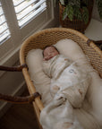 Newborn baby photography, sleeping in a wicker bassinet with pop yat tot swaddle
