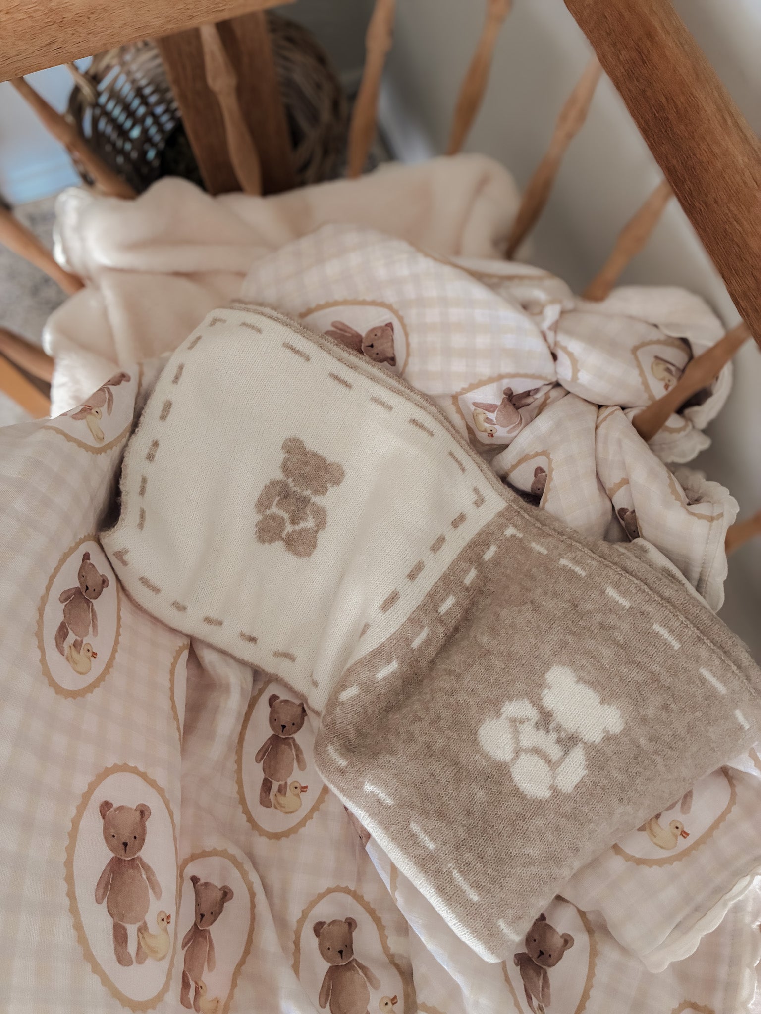 Baby blanket with teddy bear pattern draped over a wooden cradle