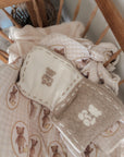 Baby blanket with teddy bear pattern draped over a wooden cradle