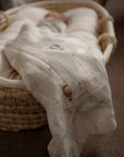 White textured blanket draped over a wicker basket on a carpeted floor