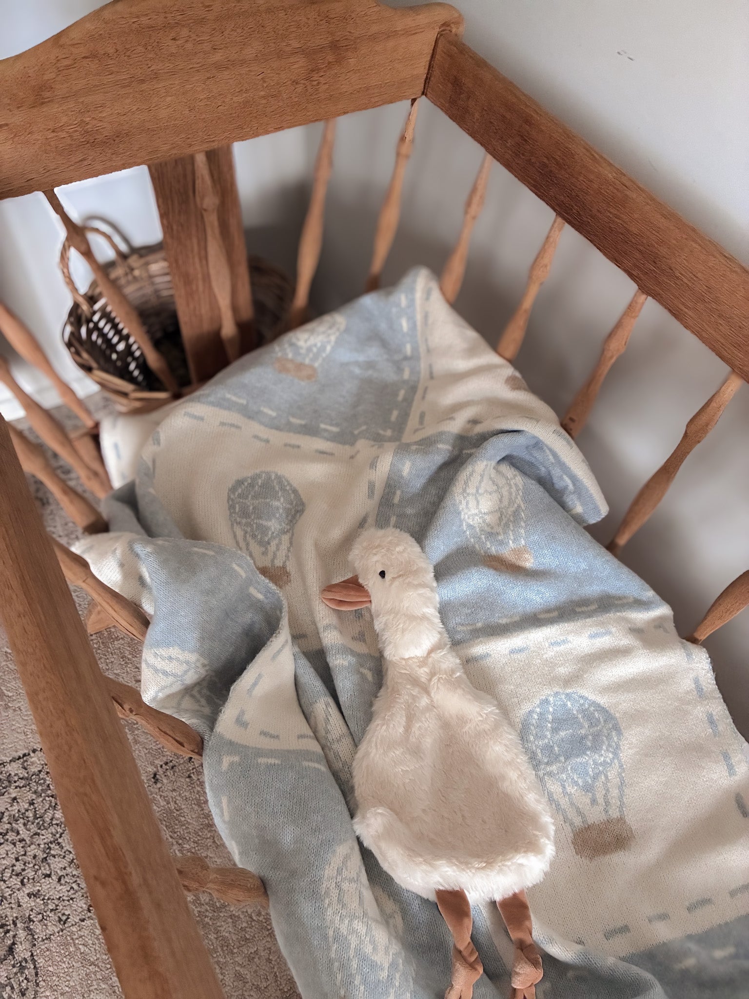 Blanket with duck design draped over a vintage cradle