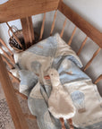 Blanket with duck design draped over a vintage cradle