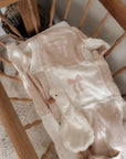 Baby blanket with bow design draped over a vintage cradle