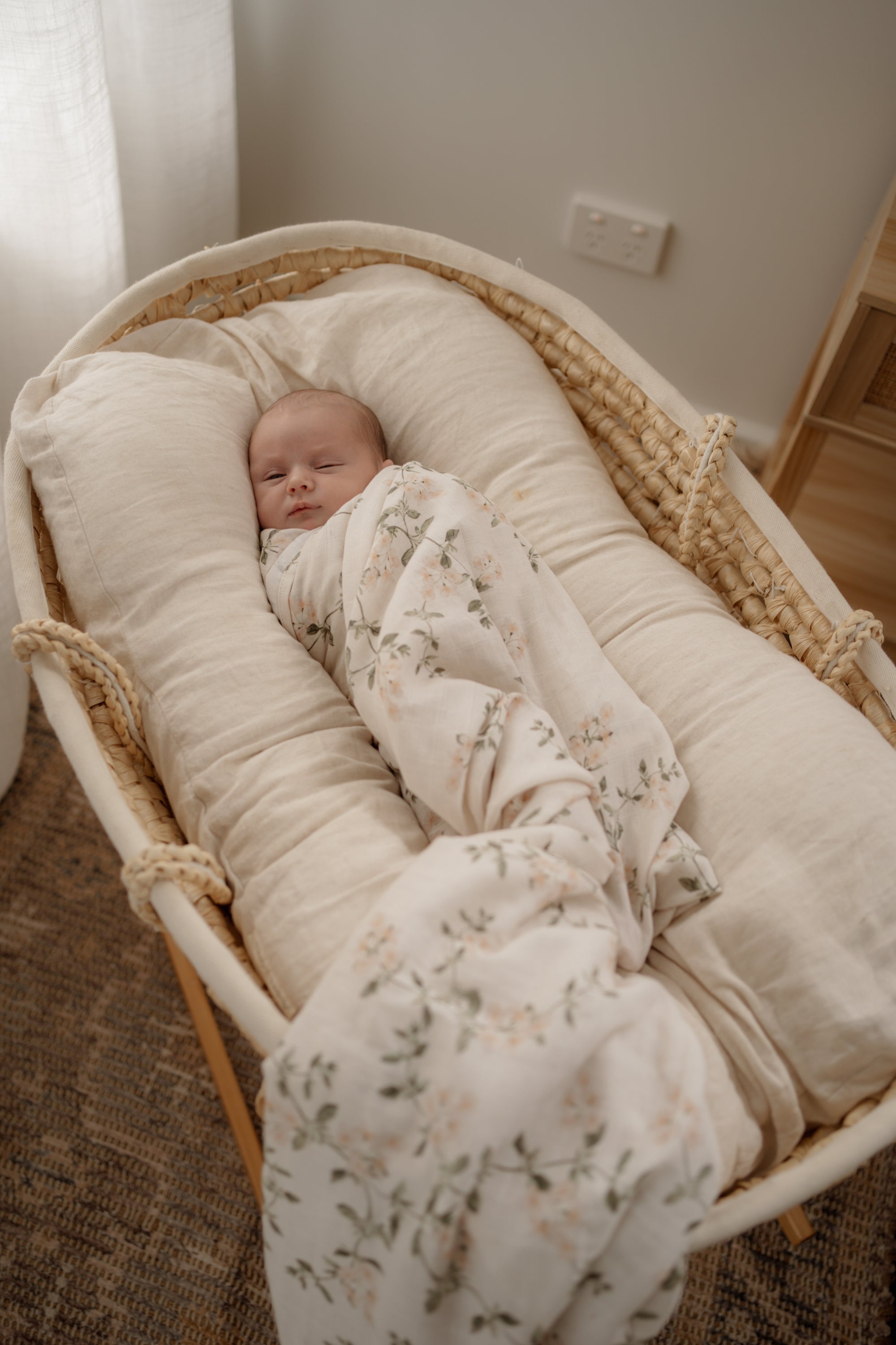 Newborn baby wrapped in a vintage floral blanket wrap