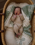 Newborn baby in a woven basket with green and white tennis patterned blankets