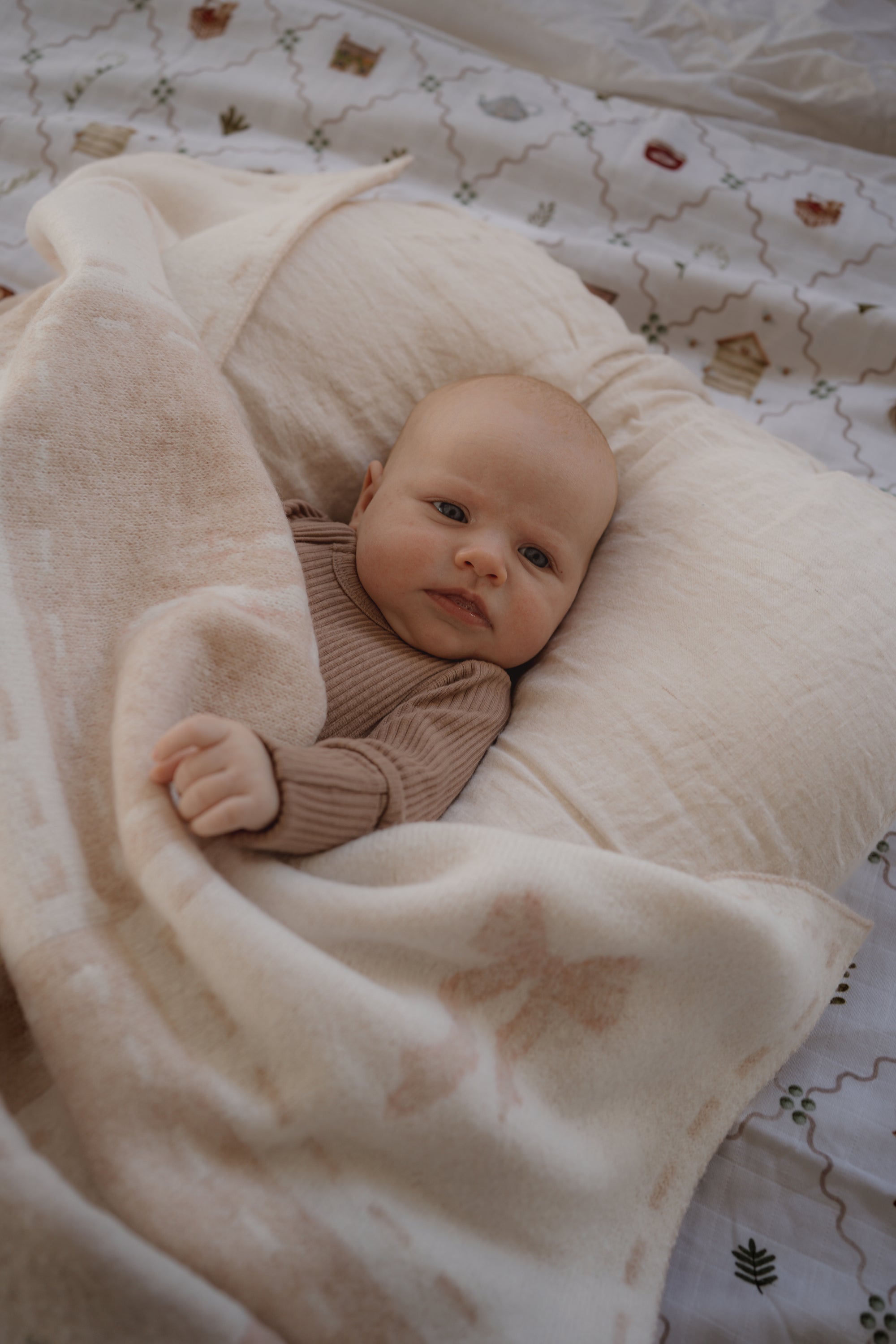 Baby lying on a white pillow with a pink bow patterned blanket