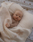 Baby lying on a white pillow with a pink bow patterned blanket