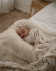 Newborn baby wrapped in a floral blanket lying on a soft pillow in a cozy room.