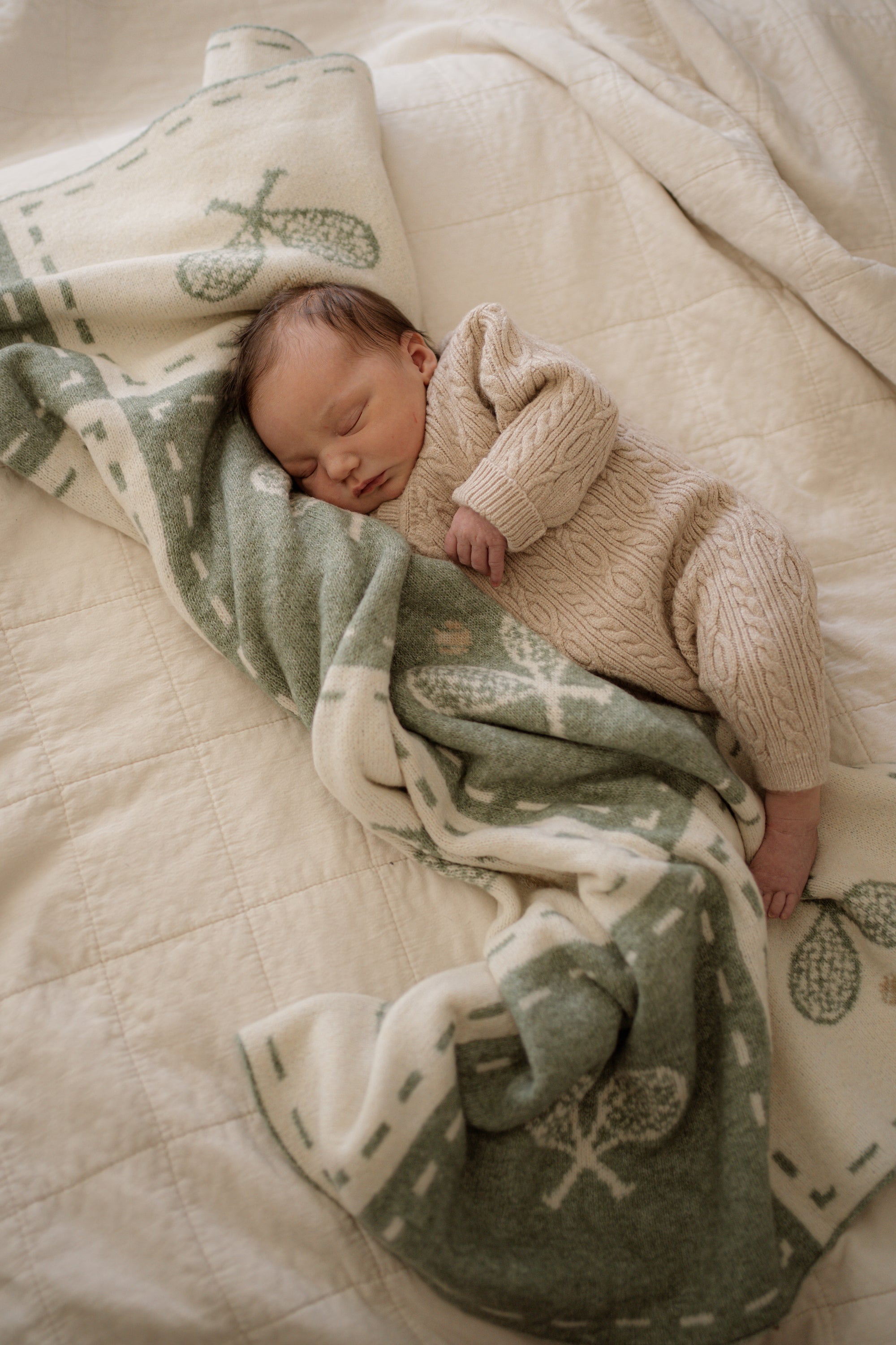 Newborn baby wrapped in a green and white tennis blanket 